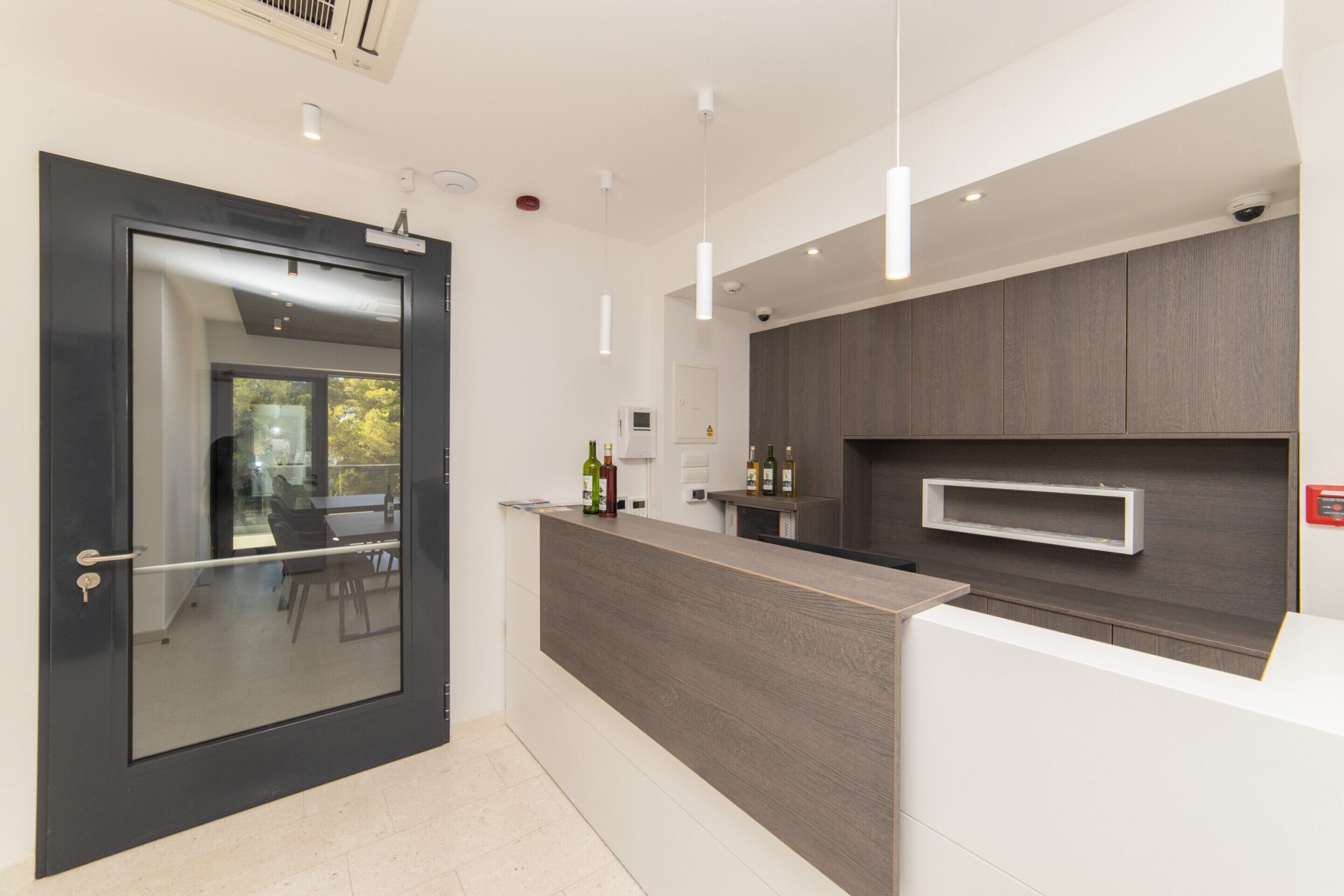 Cozinha moderna com bancada de madeira escura, porta de vidro e vista para o exterior.
