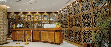 A reception desk with a wooden finish, surrounded by a decorative wooden partition with geometric patterns.