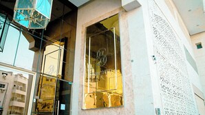 Fachada de edificio con amplios ventanales reflectantes, un escaparate visible con señalización y una estructura metálica decorativa sobre la entrada.