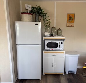 Eine kompakte Küchenzeile mit Kühlschrank, Mikrowelle und kleinen Schränken.