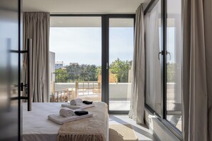 Ein Schlafzimmer mit Bett, Fenster und Blick nach draußen.