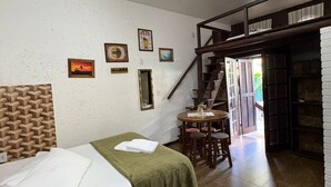 A room with a bed, a table, a staircase, and a bookshelf. - recanto  (Garopaba)