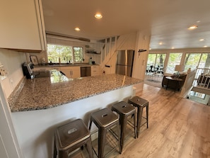 A modern kitchen with granite countertops, stainless steel appliances, and a bar area with stools.