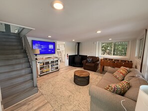 A living room with a sofa, a coffee table, a television, a fireplace, and a window with a view.