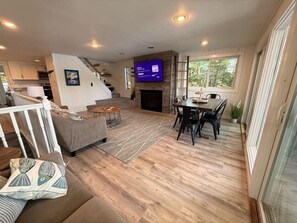 A modern living room with a fireplace, a dining area, and a staircase leading to another level.