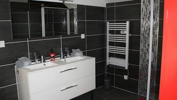 A modern bathroom with a double sink vanity, a mirror, a towel rack, and a shower area.