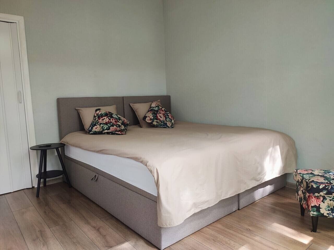 A bedroom with a bed, a small side table, and a chair.