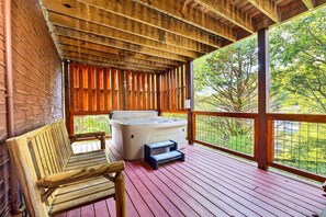 Un terrazzo in legno con idromassaggio e una panca, circondato da una recinzione in legno e un muro in mattoni.