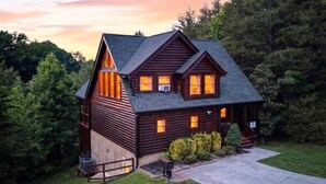 A log cabin with a steep roof, multiple windows, and a front porch.