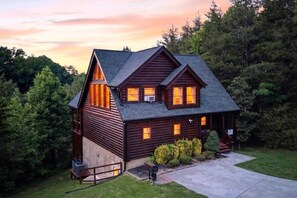 Eine Blockhütte mit einem steilen Dach, mehreren Fenstern und einer Veranda.