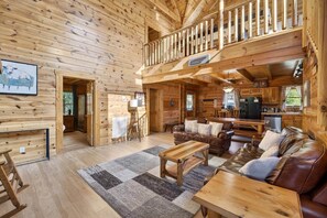 Eine Holzhütte mit Essbereich, einem Wohnzimmer mit Ledermöbeln und einer Küche.