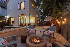 Ein modernes Haus mit Feuerstelle, Sitzgelegenheiten im Freien und einem Pool.