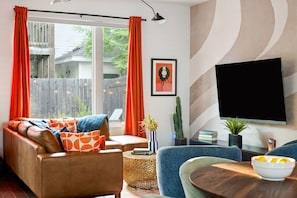 A living room with a sofa, a coffee table, a television, and a cactus plant. - Rainey Escape / Pool / Hot Tub / Fire Pit / DT ATX (Austin)