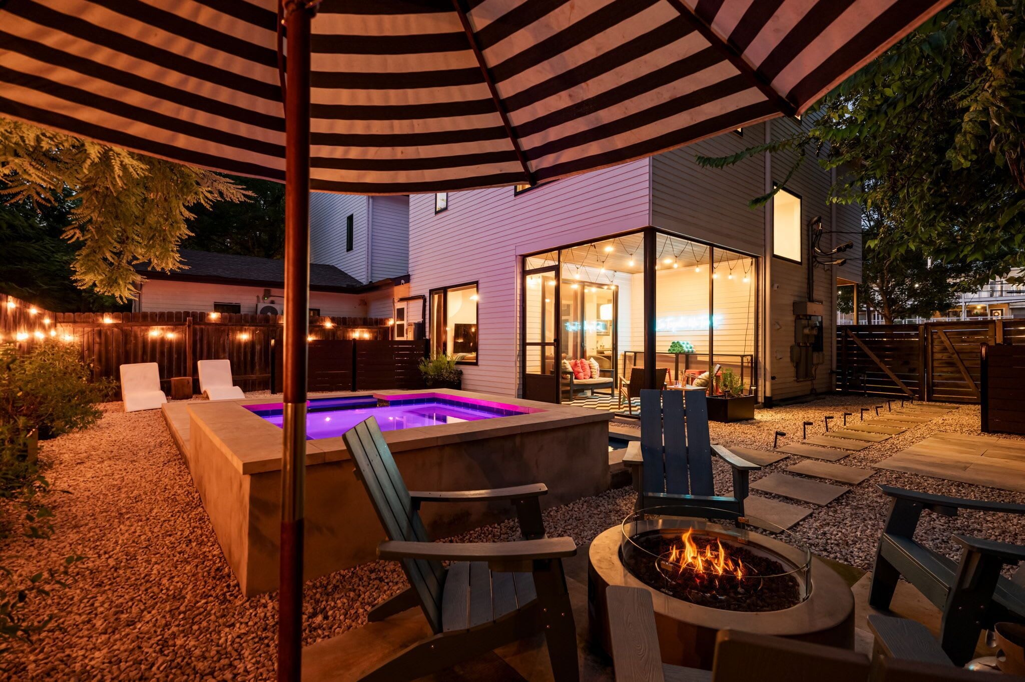 Eine Außenpatio-Terrasse mit Pool, Sitzgelegenheiten und einer Feuerstelle.
