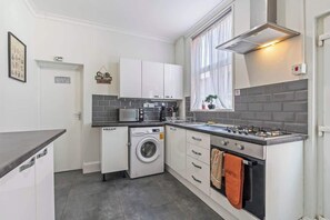 A modern kitchen with a built-in washer, oven, and microwave. - Spacious 4BDR | Ideal for Contractors |City centre (Coventry)