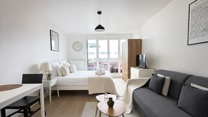 Moderni hotellihuone, jossa on sänky, sohva, työpöytä ja televisio.