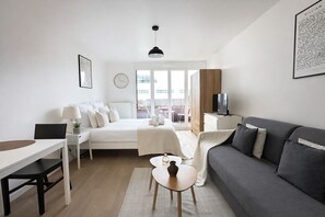 Ein modernes Hotelzimmer mit Bett, Sofa, Schreibtisch und Fernseher.