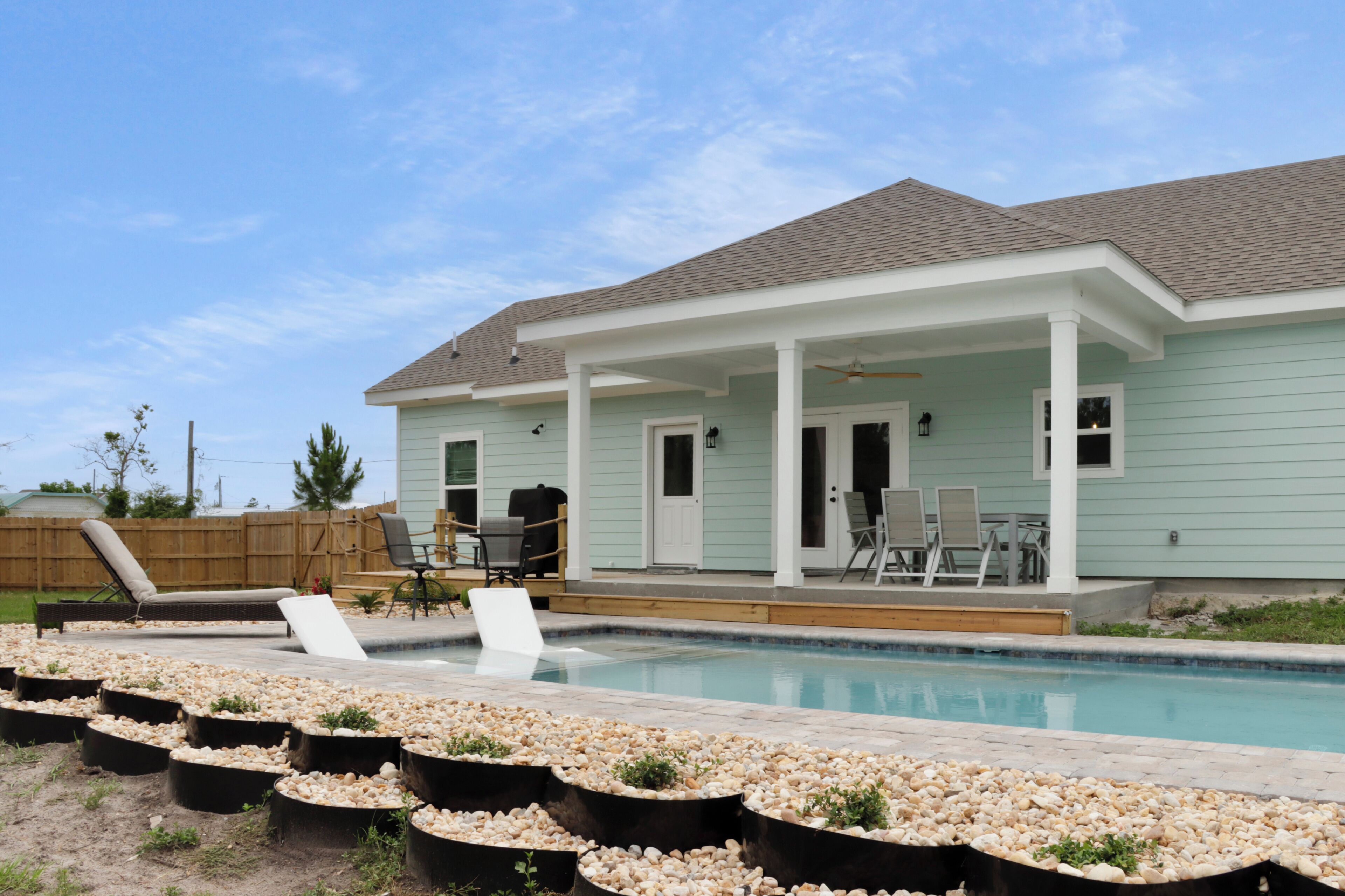 Ein Haus mit Swimmingpool, Sitzgelegenheiten im Freien und einer überdachten Terrasse.