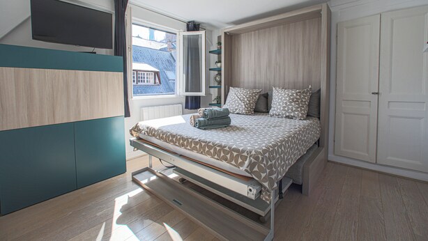 Una camera da letto con un letto, una TV a parete e una finestra.