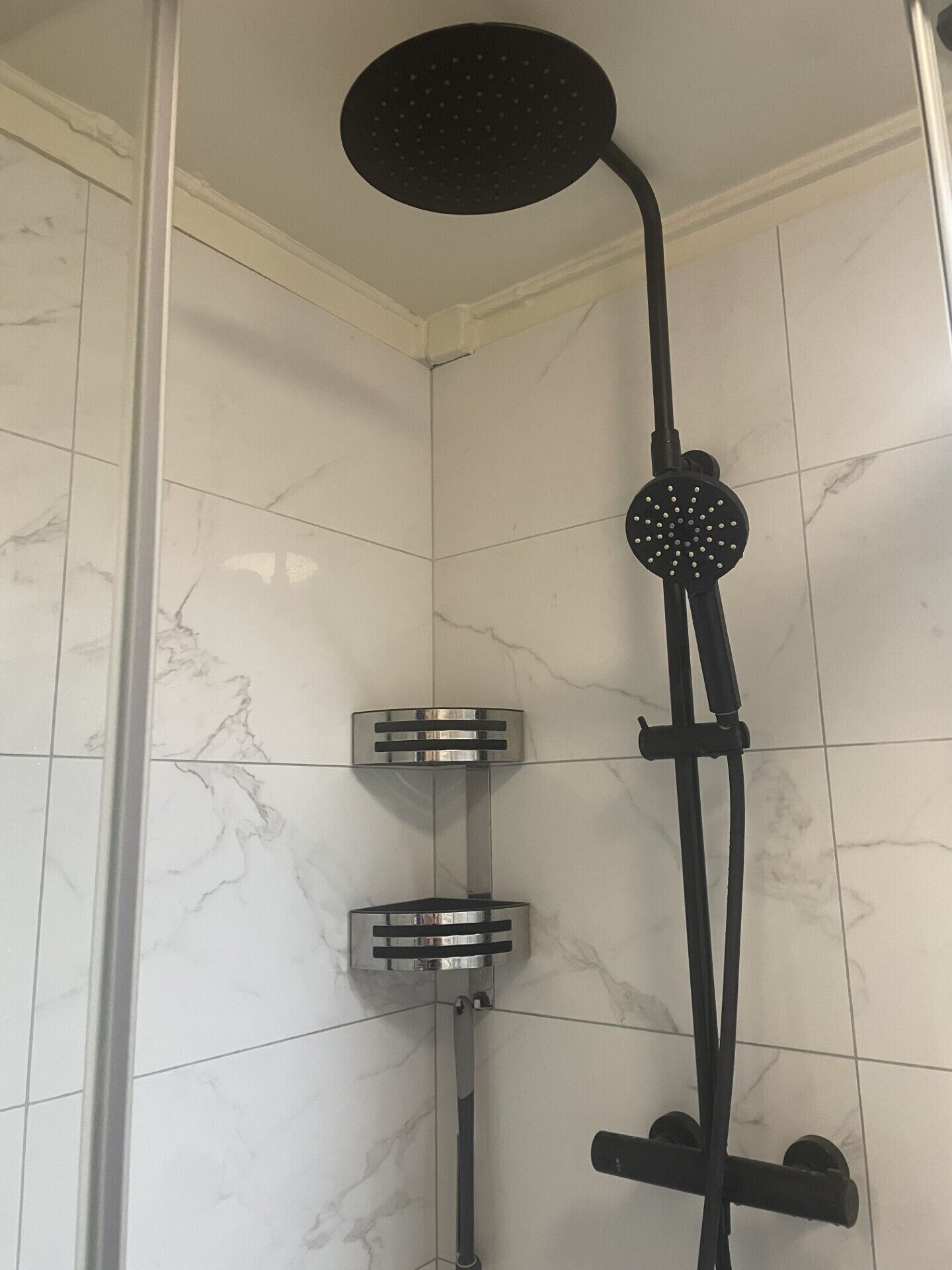 Une douche équipée d’un pommeau de douche à effet pluie, de deux pommes de douche à main et d’un flexible de douche.