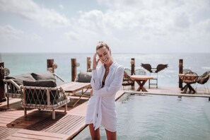 Eine Person steht an einem Pool mit Liegestühlen und Blick auf den Ozean.