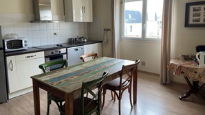 Et køkken med hvide skabe, en mikrobølgeovn, en komfur og et spisebord med stole.
