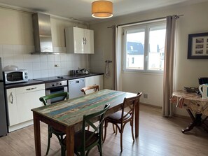 Une cuisine avec des meubles blancs, un four à micro-ondes, une cuisinière et une table à manger avec des chaises.