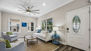 Un salon doté d’un ventilateur de plafond, de deux canapés, d’une table basse et d’une porte ornée d’un vitrail.