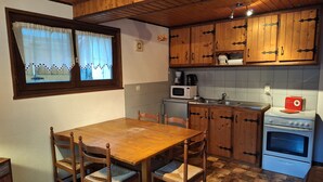 Una cocina con armarios de madera, una mesa de comedor, sillas, un microondas, una cafetera, un tostador y un horno.