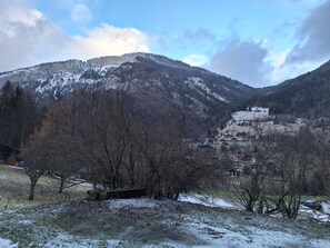 Un paisaje montañoso con picos nevados, un valle con vegetación escasa y un pequeño poblado con edificios tradicionales.