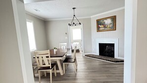 Una sala de estar amplia con chimenea, comedor y candelabro.