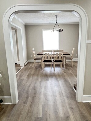 A dining area with a table and chairs, a chandelier, and a view through a doorway. - Mins from Duke Hospital and UNC Chapel Hill (Durham)