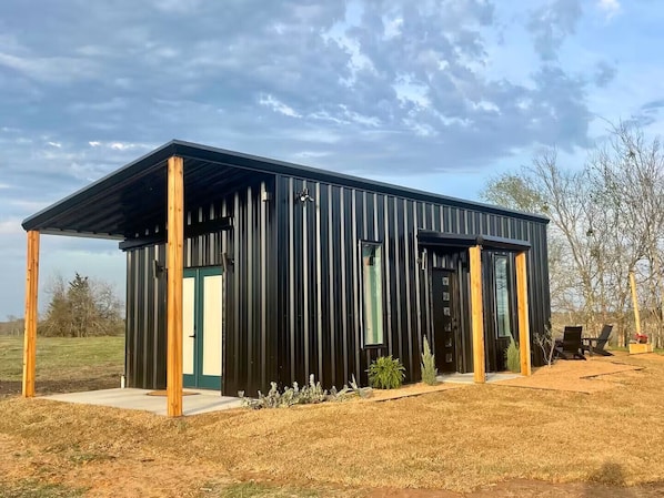 Un bâtiment moderne en métal, doté d’un toit plat, de grandes fenêtres et d’une entrée abritée.