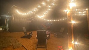 Een terras buiten met lichtjes, stoelen en een tafel.