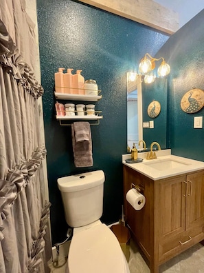 Une salle de bain comprenant des toilettes, un lavabo, un meuble-lavabo et des miroirs décoratifs.