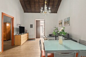 Un espace repas comprenant une table en verre, des chaises, un lustre et des œuvres d’art accrochées aux murs.