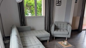 Ein modernes Wohnzimmer mit einem Ecksofa, einem Sessel, einem Glastisch und einer Lampe.