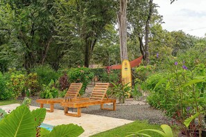A garden with wooden lounge chairs, a yellow structure, and various plants. - 2BR/2BA Retreat pool parking rancho, Walk to Beach (Playa Grande)