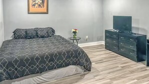 Quarto com cama, penteadeira, televisão e quadro na parede.