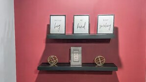 Pared vermelha com três prateleiras exibindo frases motivacionais e duas esferas decorativas.