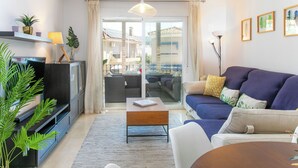 Un salon moderne avec un canapé, une table basse, un téléviseur et des plantes.