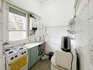 Uma cozinha com fogão a gás, micro-ondas e chaleira.