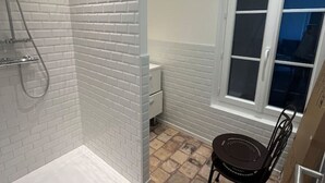 Un baño con paredes de ladrillo blanco, una bañera blanca, una ventana con vistas y una silla.