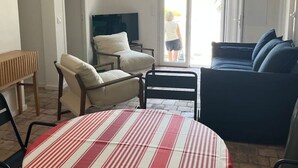 Una sala de estar con una mesa a rayas, un sofá, una silla y un televisor.