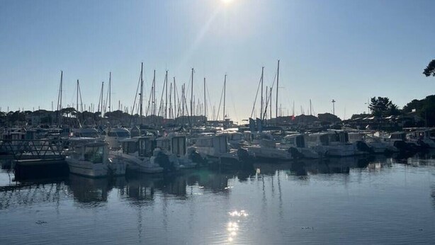 Un puerto deportivo con barcos amarrados, agua tranquila y cielo despejado.