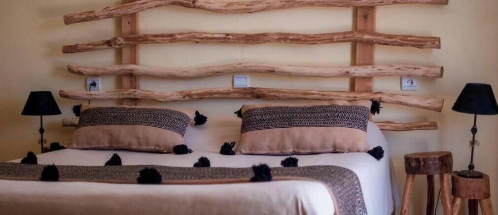 Un letto con una testiera in legno, due lampade ai comodini e un tavolino.