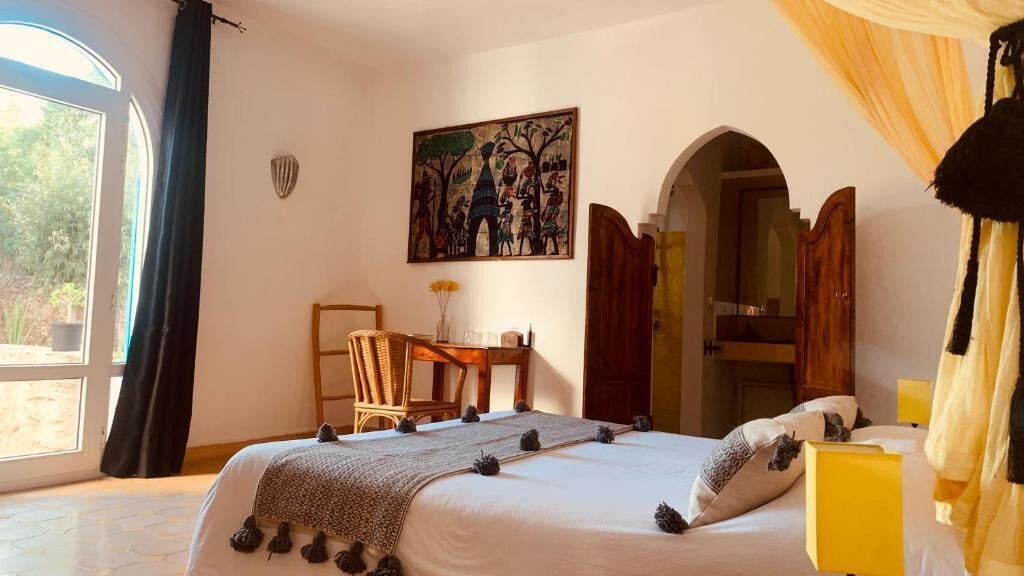 Une chambre avec un grand lit, un bureau et un tableau accroché au mur.