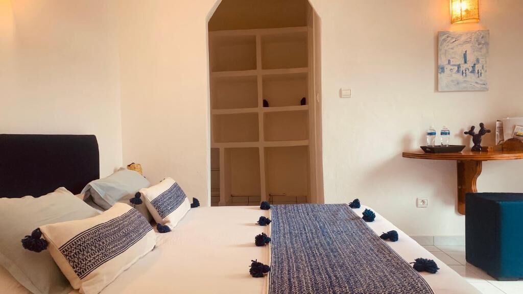Un dormitorio con cama, mesitas de noche, armario y escritorio con silla.