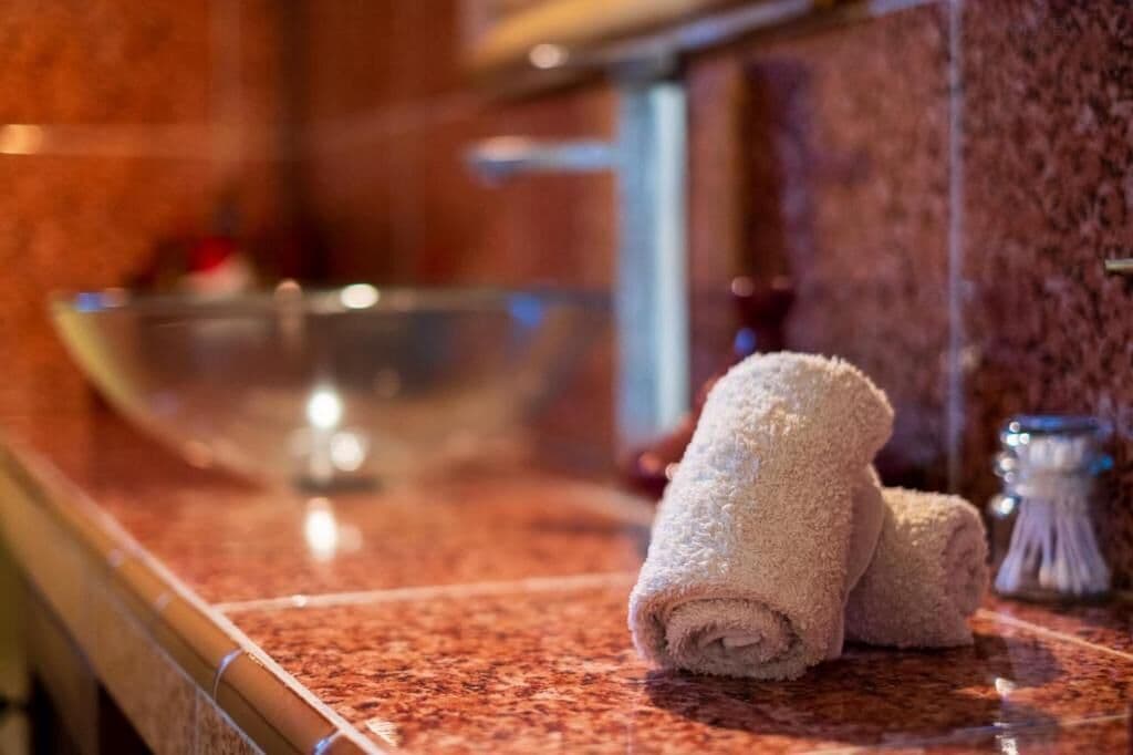 Un baño con encimera de mármol, un lavabo y toallas enrolladas.