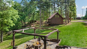 A stone patio with a fire pit, wooden chairs, and a pergola structure. - Pine Haven-Serene & Natural Cabin-7 mi to Downtown (Eureka Springs)